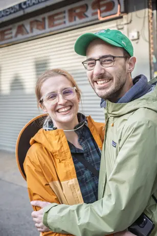 Cute couple laughing and smiling toward the camera while enjoying picking up trash